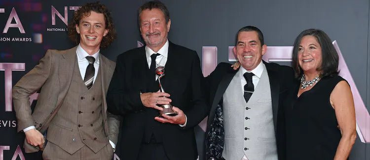 Pressefoto von den National Television Awards: vier Gäste vor der Logowand, einer hält die Trophäe