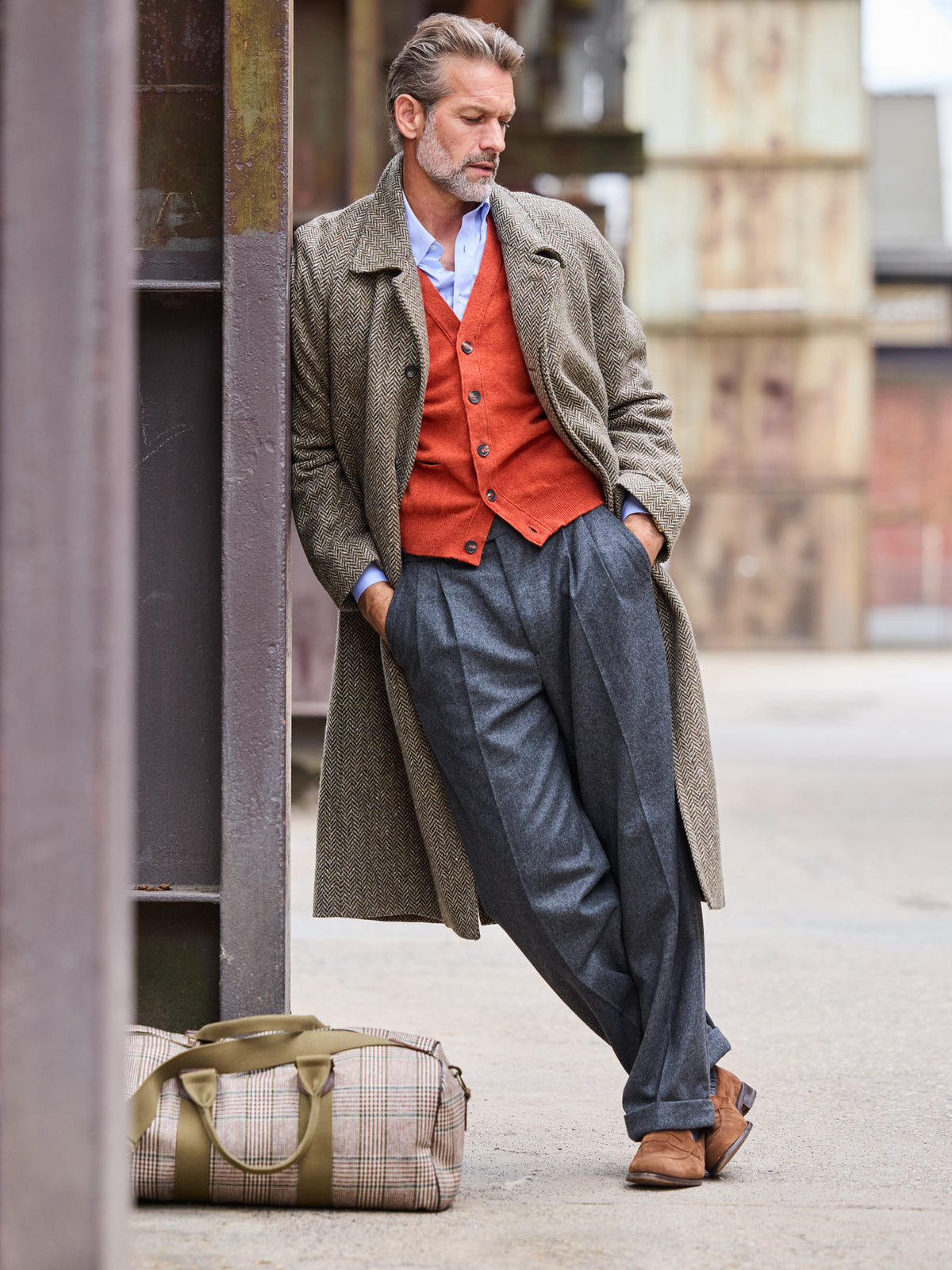 Weekender Prince-of-Wales-Karo Lovat Tweed Beige am Boden abgestellt, daneben Model im Raglanmantel — John Crocket