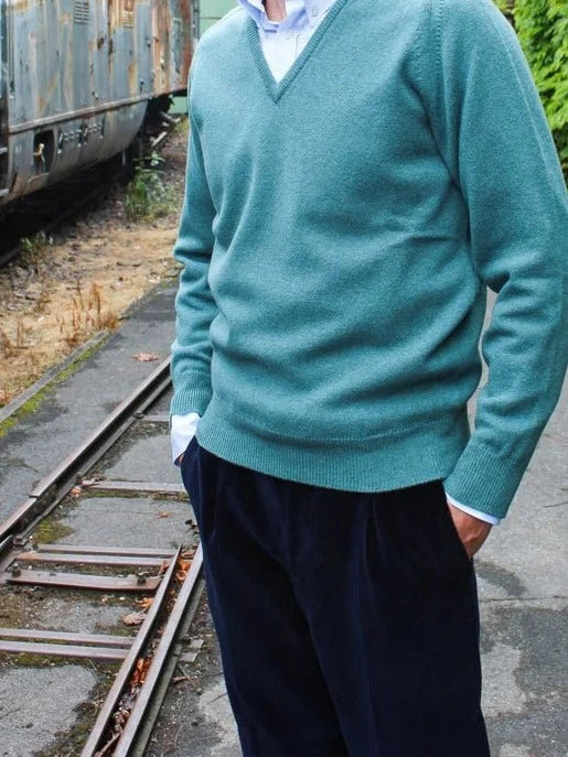 Lambswool Pullover mit V-Ausschnitt in Türkisgrün, am Model getragen mit hellblauem Hemd und dunkler Cordhose – John Crocket