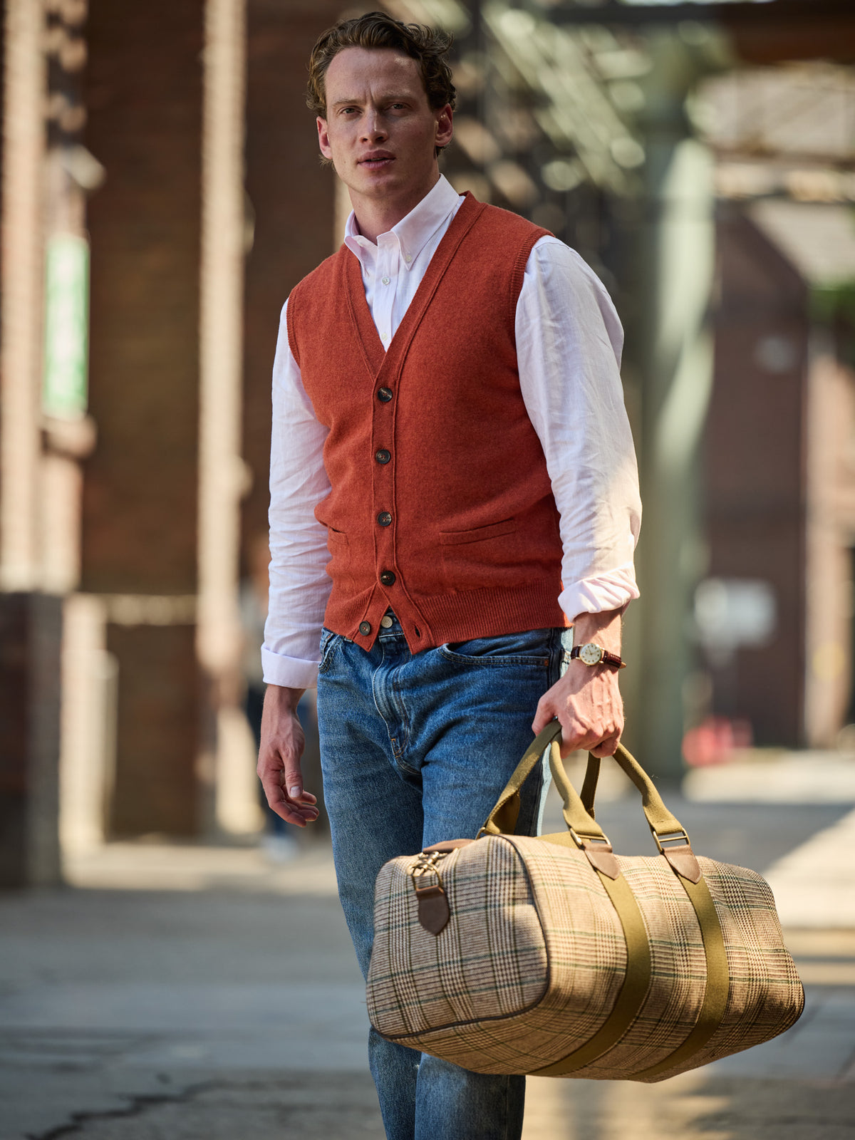 Weekender Prince-of-Wales-Karo Lovat Tweed Beige am Model in der Hand, zu Strickweste und Jeans — John Crocket